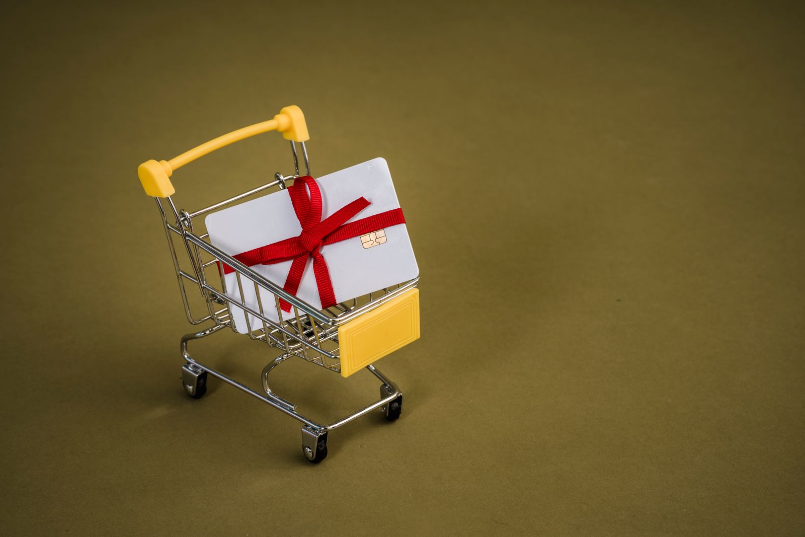 Une carte cadeau avec un nœud rouge dans un petit caddie