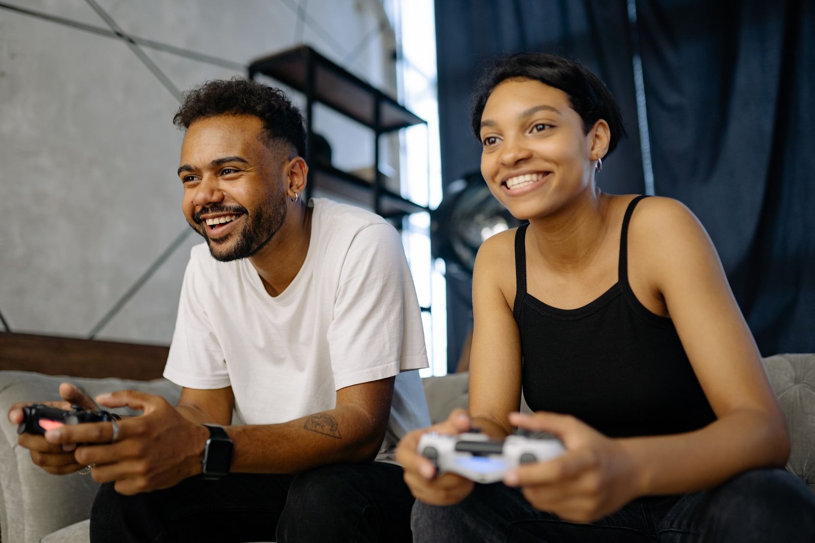A couple playing video games on a sofa, smiling